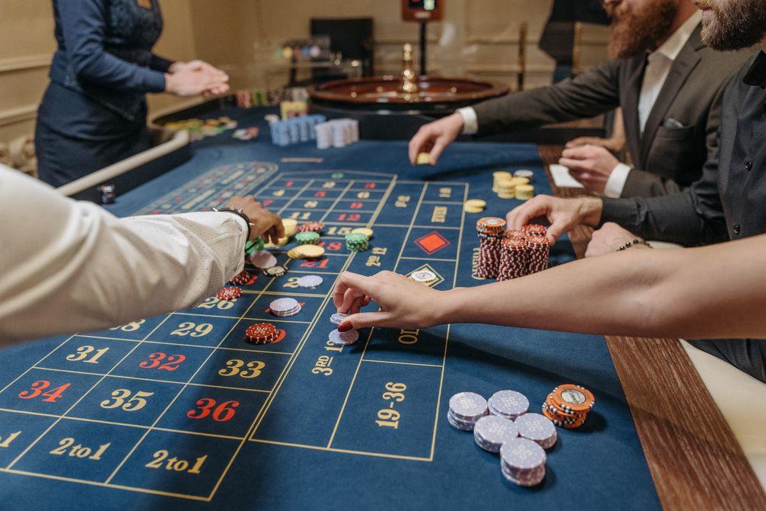 Meja roulette dengan dealer dan pemain memasang taruhan